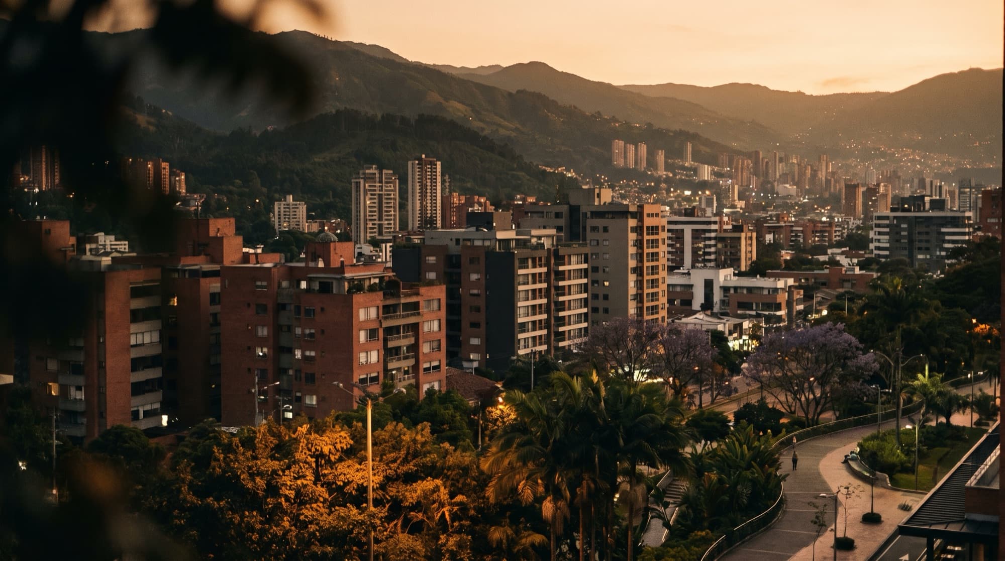 Golden-hour skyline of a modern Colombian city framed by green hills