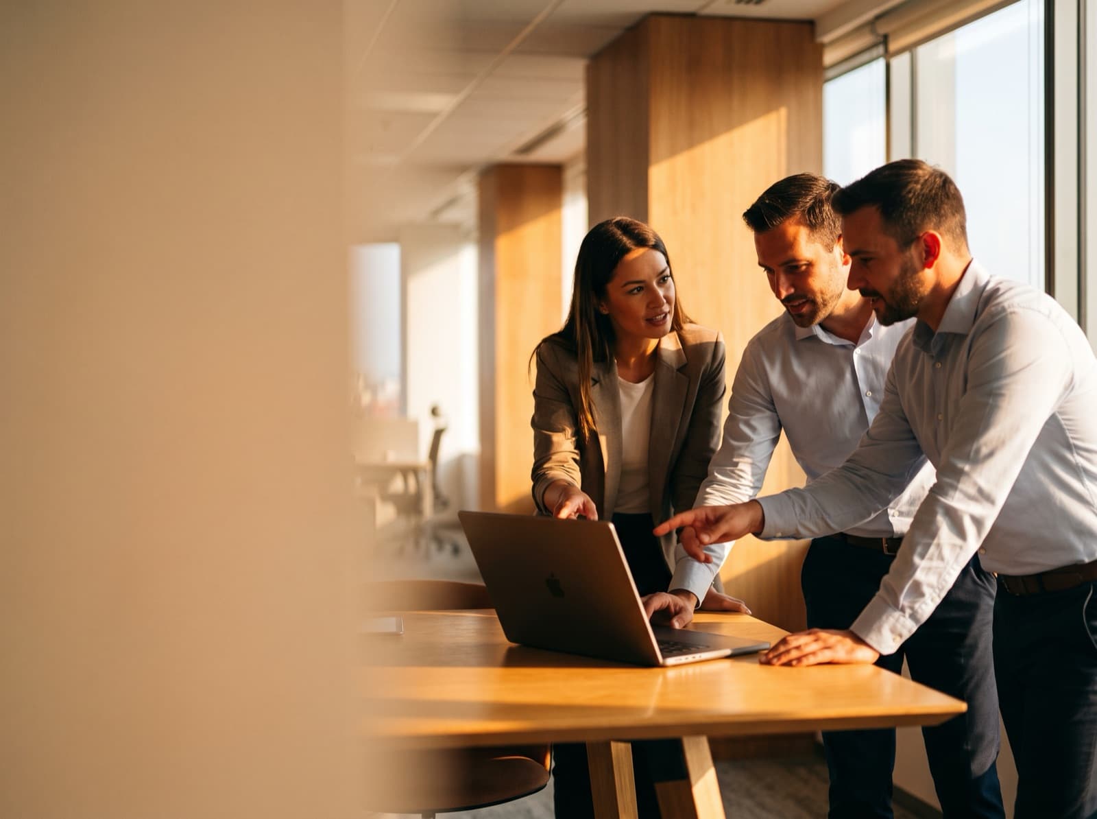 An insurance customer-experience team collaborating around a laptop in a modern office