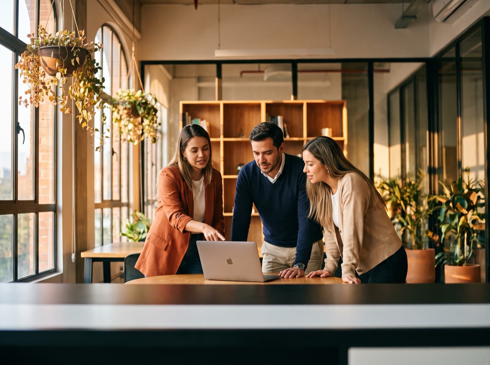 A team of Colombian customer-experience professionals collaborating around a laptop in a modern office