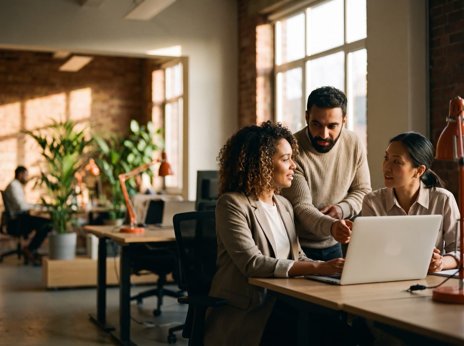 A team of American customer-experience professionals collaborating around a laptop in a modern office