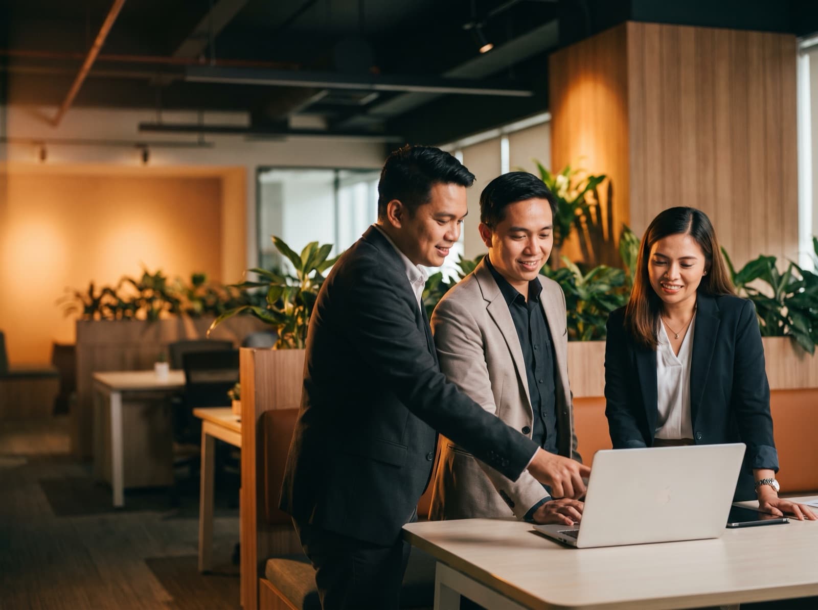 A team of Filipino customer-experience professionals collaborating around a laptop in a modern office